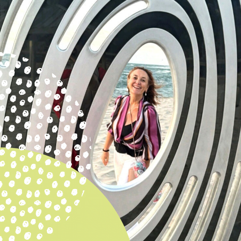 woman at the beach smiling through an art sculpture